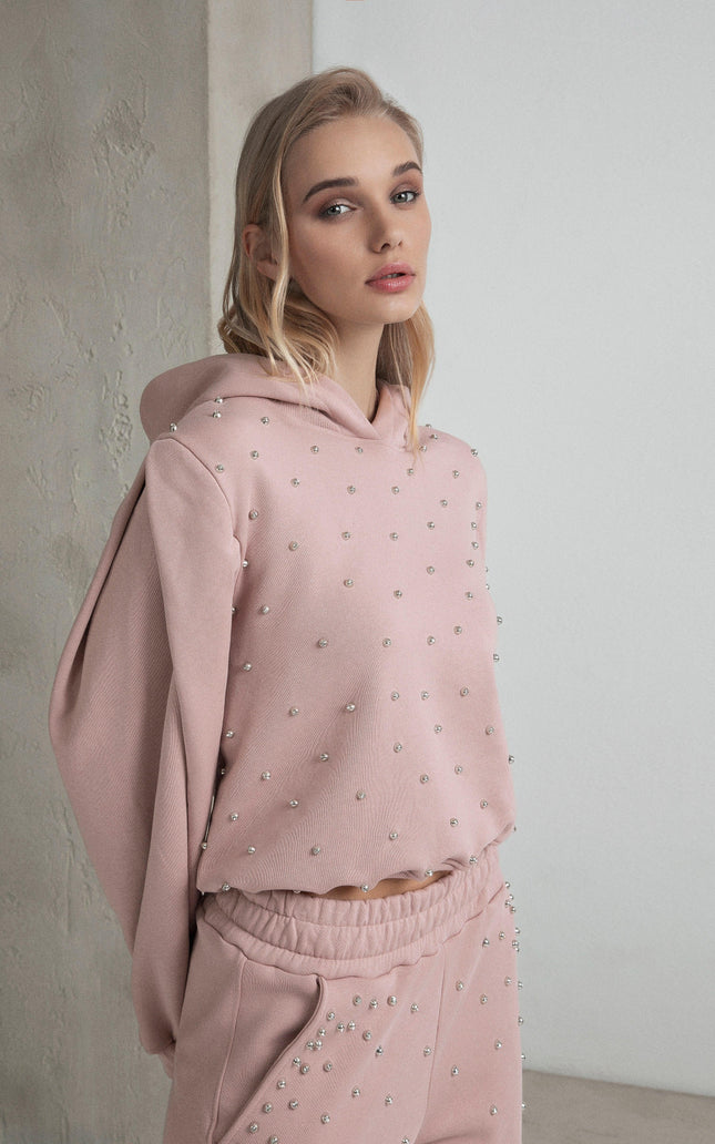 Woman wearing a pink embellished hoodie and matching pants, modern casual fashion