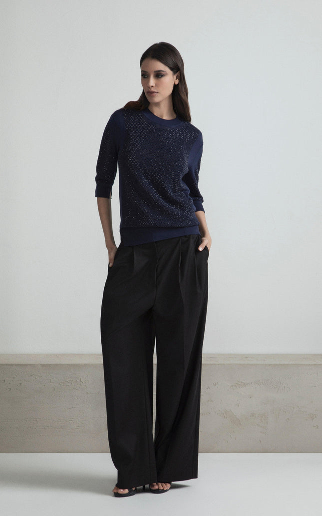 Woman wearing navy blue embellished sweater and black wide-leg pants, fashion look