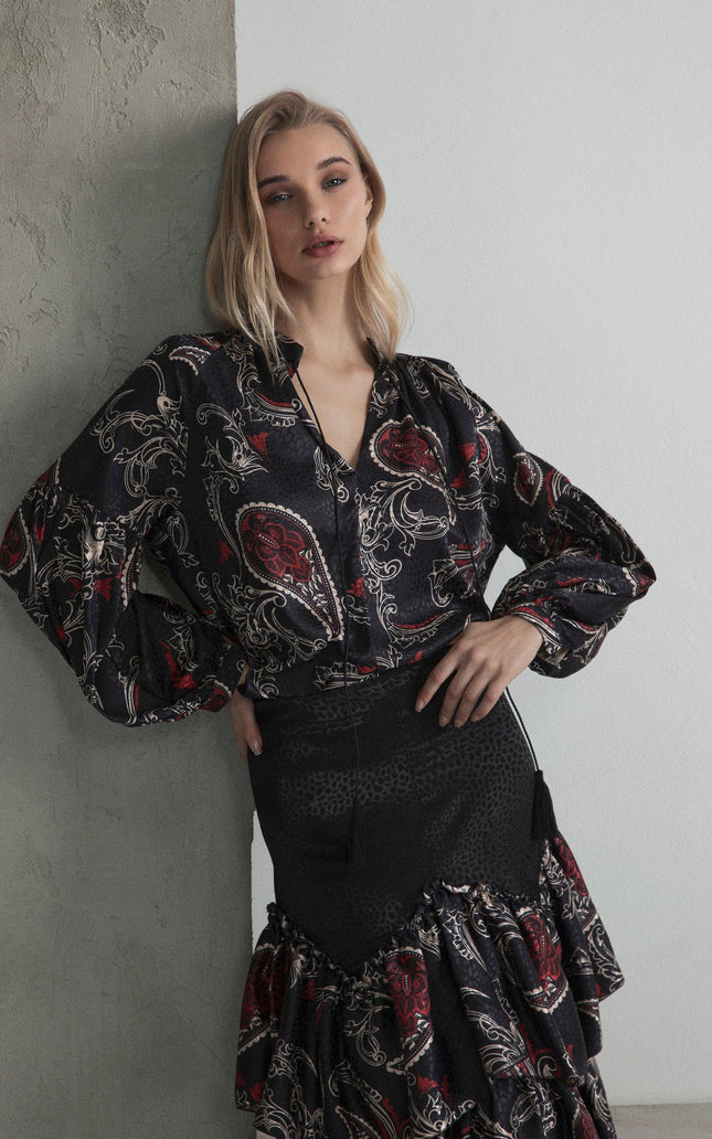 Woman wearing a black paisley print blouse and matching ruffled skirt, modern fashion look