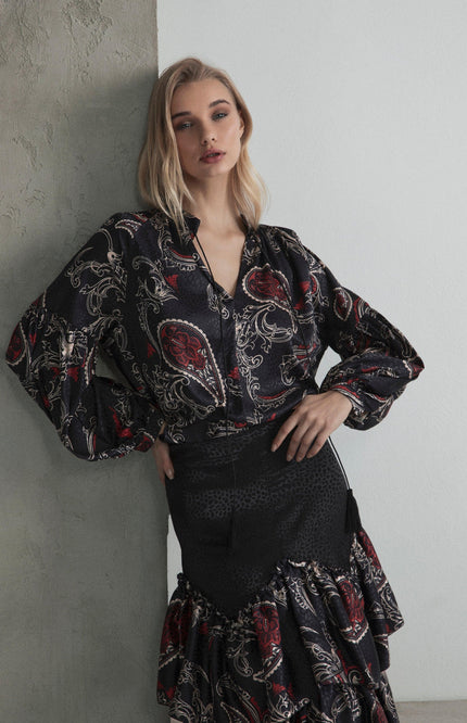Woman wearing a black paisley print blouse and matching ruffled skirt, modern fashion look