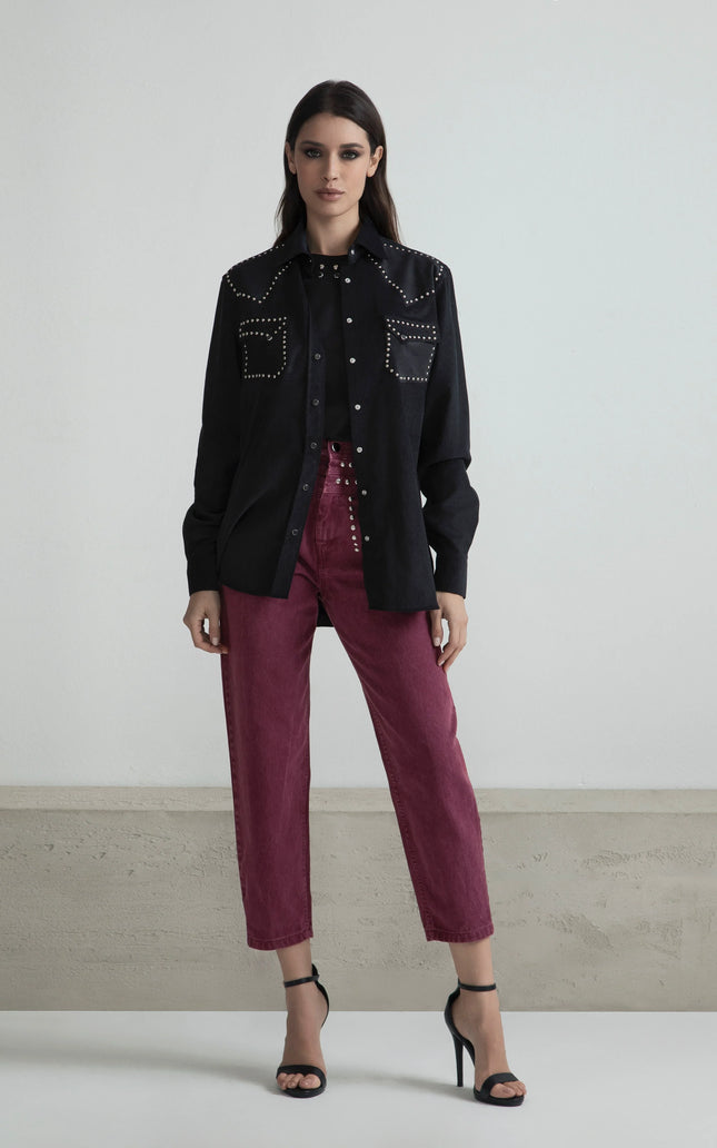 Woman in a black studded shirt and high-waisted burgundy pants with heels