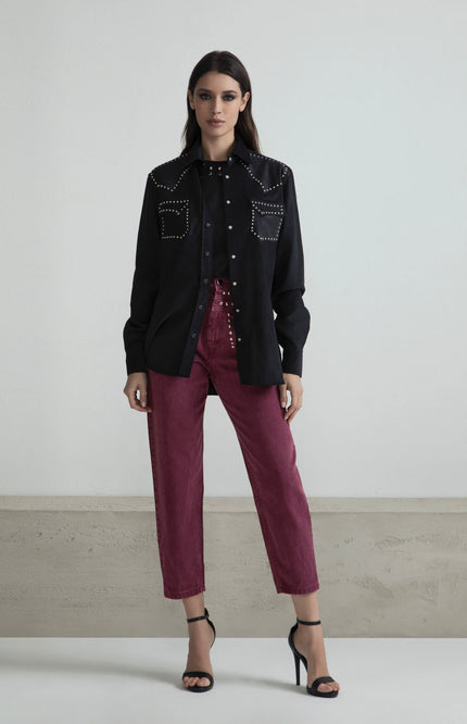 Woman in a black studded shirt and high-waisted burgundy pants with heels