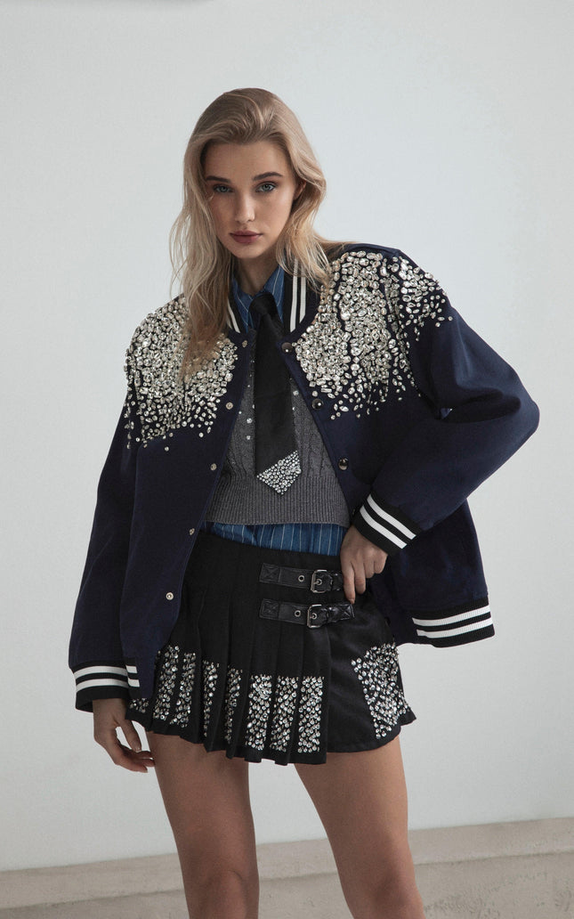 Woman in embellished varsity jacket and pleated skirt with crystal details, modern fashion look