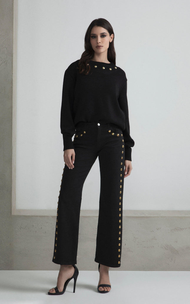 Woman wearing black sweater and pants with gold buttons, high heels, modern fashion look