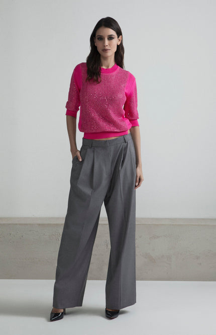 Woman wearing a sparkly pink sweater with gray wide-leg pants and black heels