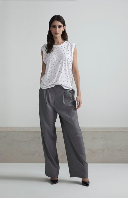 Woman wearing a white studded sleeveless top and high-waisted wide-leg gray pants