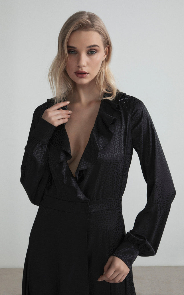 Woman wearing a black wrap dress with ruffle neckline and subtle animal print texture
