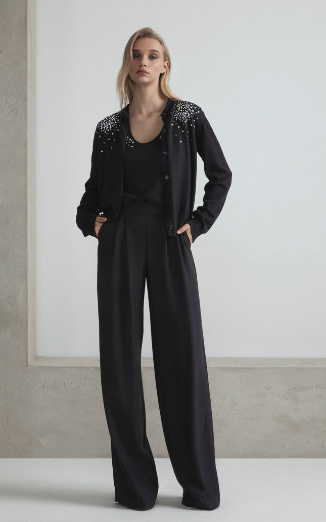 Woman wearing black embellished cardigan and wide-leg pants, modern fashion look