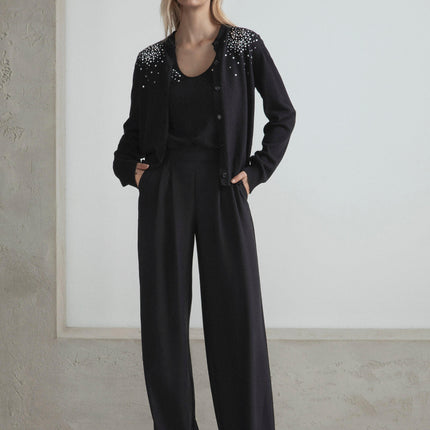 Woman wearing black embellished cardigan and wide-leg pants, modern fashion look