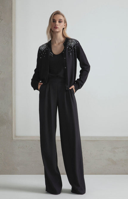 Woman wearing black embellished cardigan and wide-leg pants, modern fashion look