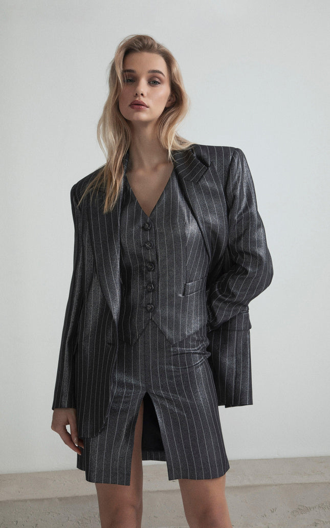 Woman wearing metallic pinstripe blazer, vest, and skirt set with front slit