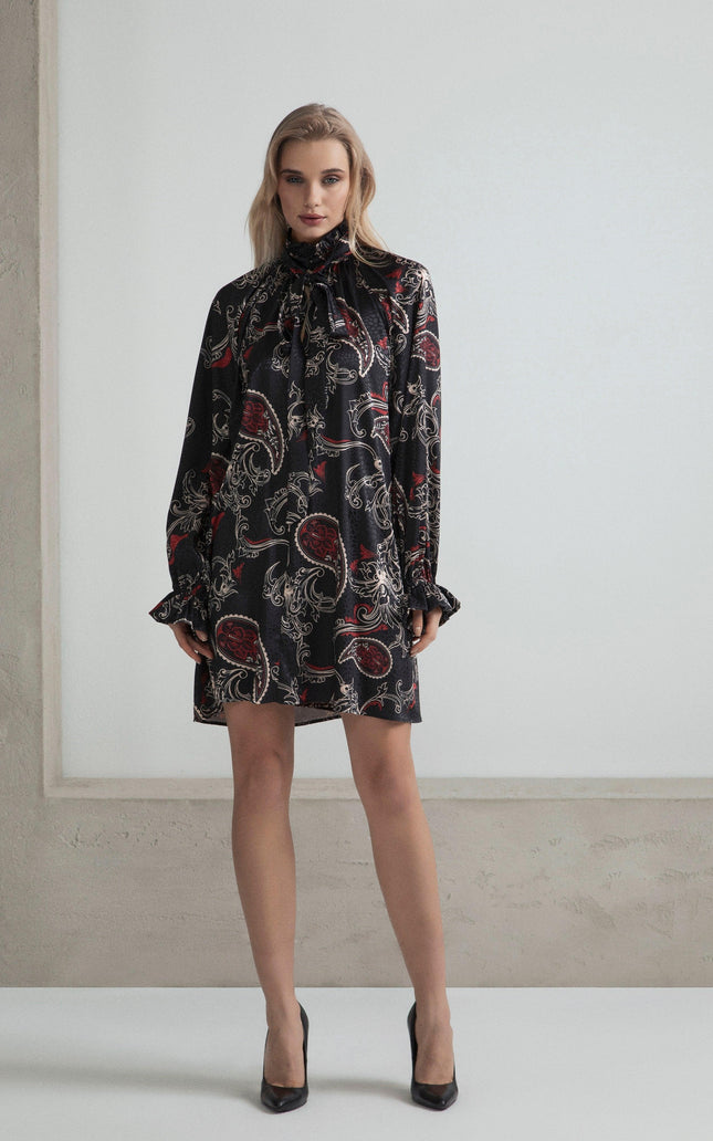 Woman wearing a black paisley print mini dress with long sleeves and ruffled cuffs
