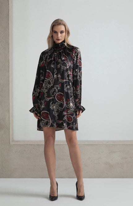 Woman wearing a black paisley print mini dress with long sleeves and ruffled cuffs