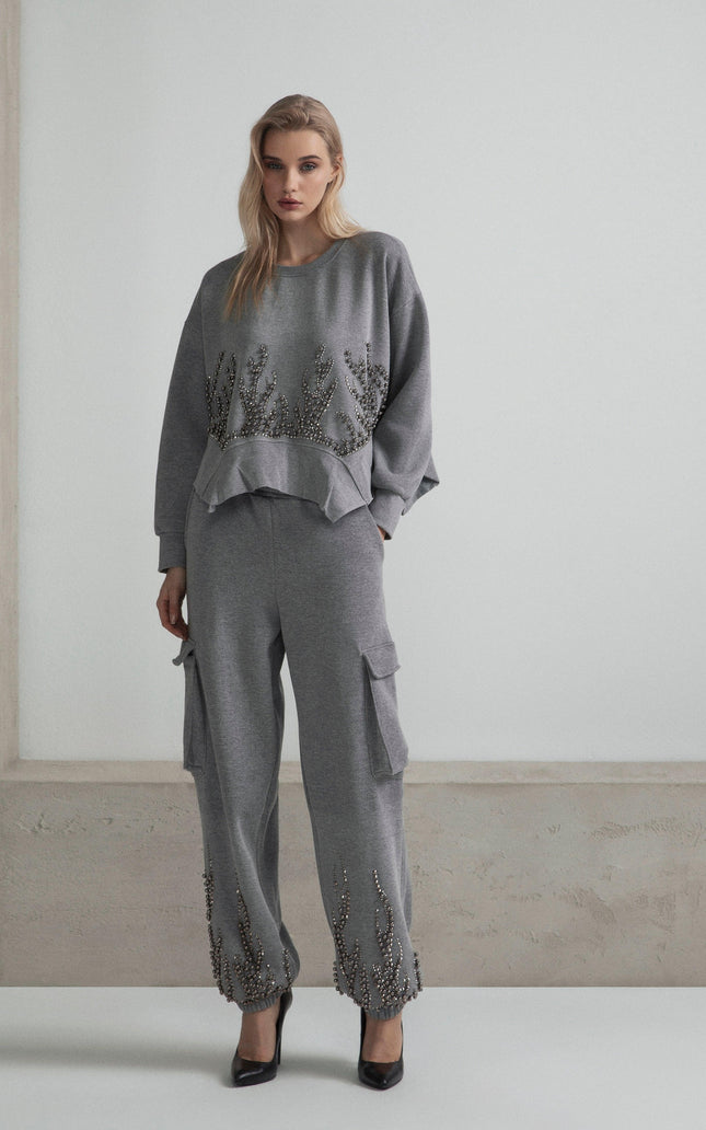 Woman in gray embellished tracksuit with cargo pants and ruffled hem details