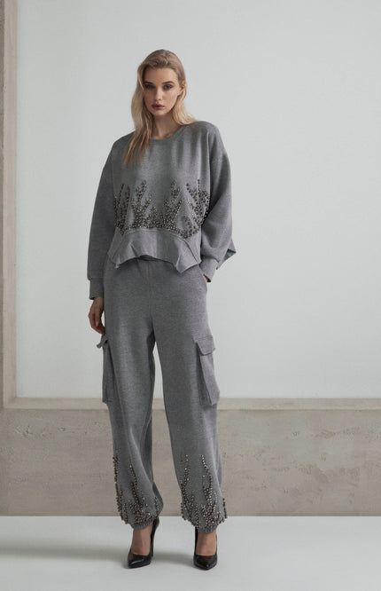 Woman in gray embellished tracksuit with cargo pants and ruffled hem details