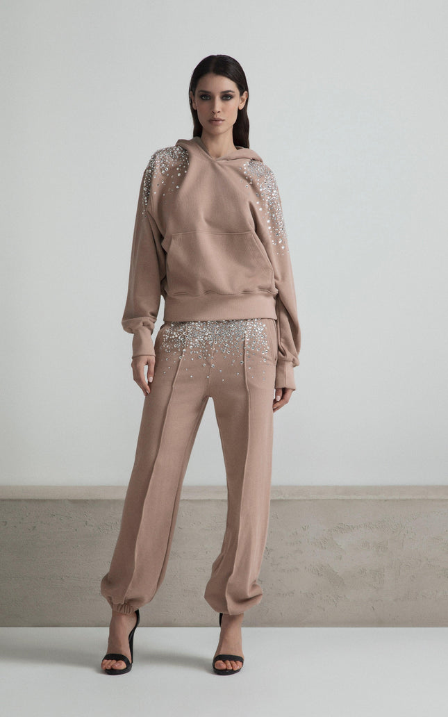 Woman in beige embellished sweatshirt and pants, standing indoors, fashion look
