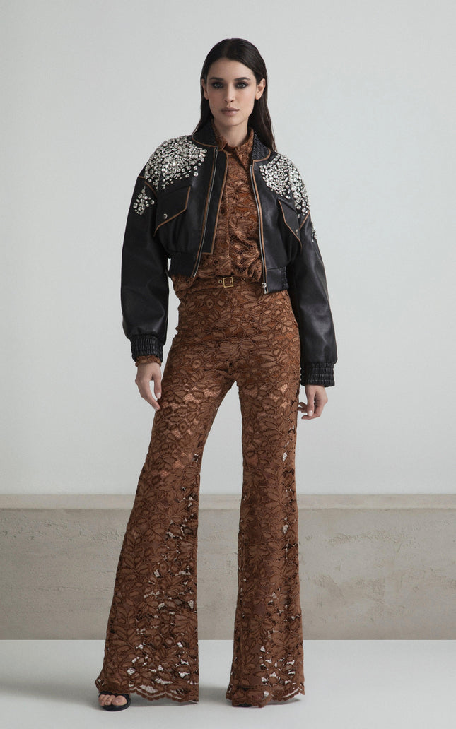 Woman in brown lace jumpsuit with flared pants and black studded leather jacket