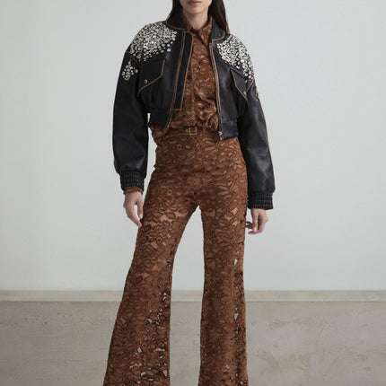 Woman in brown lace jumpsuit with flared pants and black studded leather jacket