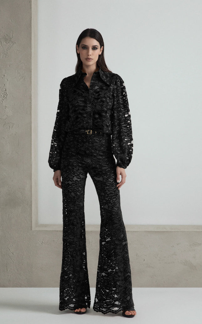 Woman wearing black lace flare pants and matching blouse with belt, fashion outfit