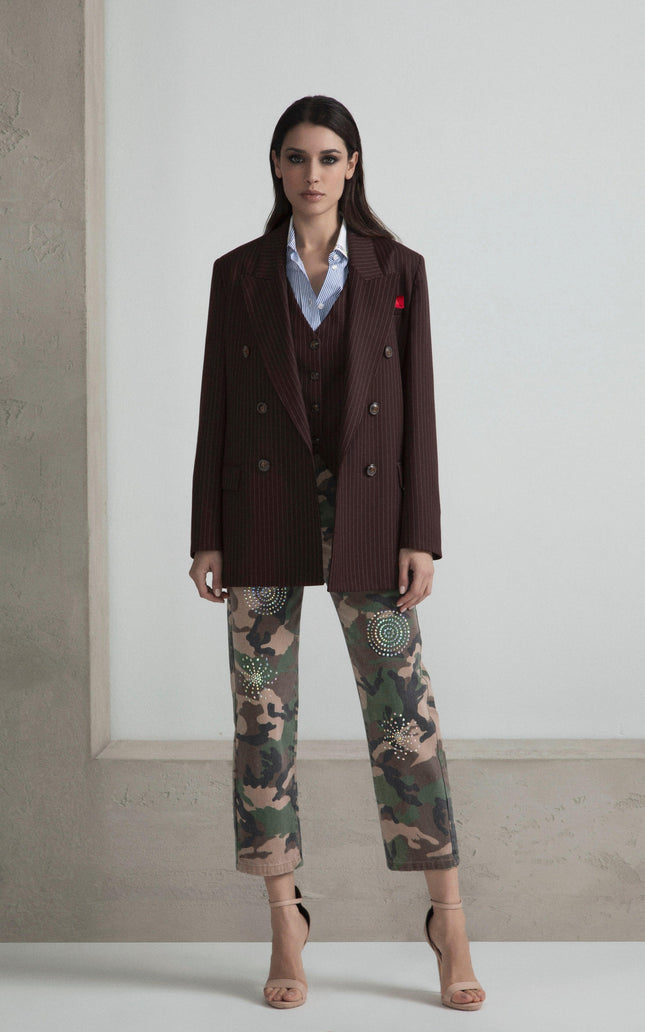 Woman in pinstripe blazer, blue shirt, embellished camo pants, nude heels, minimalist setting