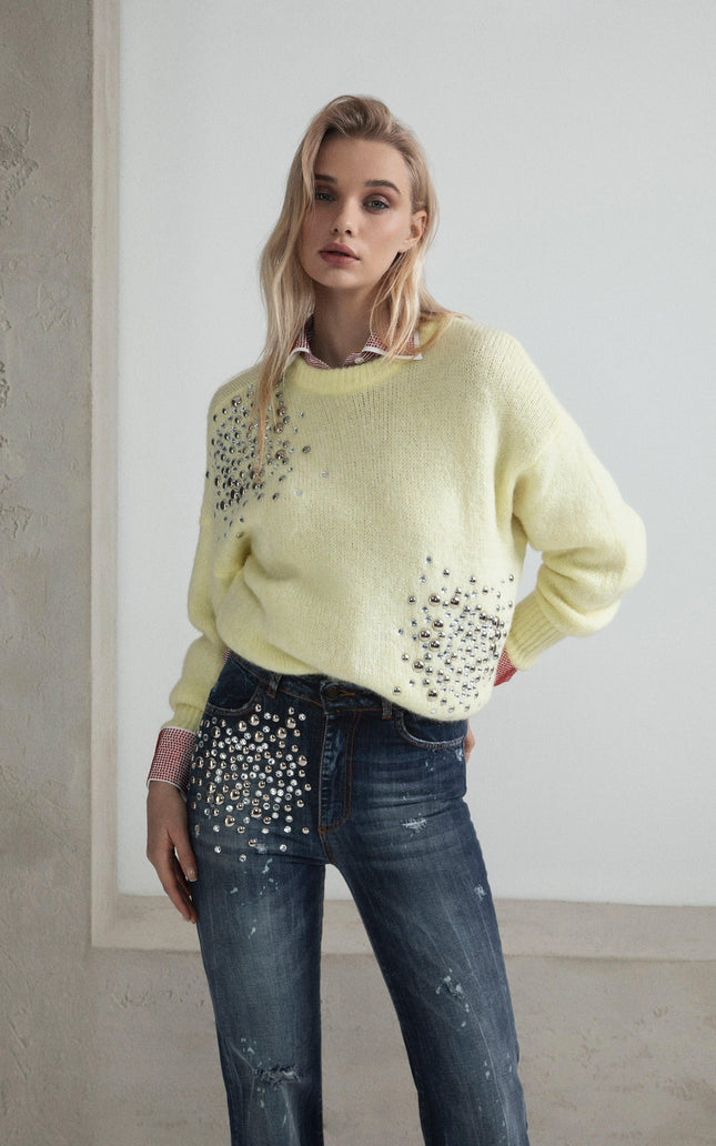 Woman in embellished yellow sweater and rhinestone-studded jeans, fashion editorial look