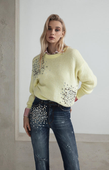 Woman in embellished yellow sweater and rhinestone-studded jeans, fashion editorial look