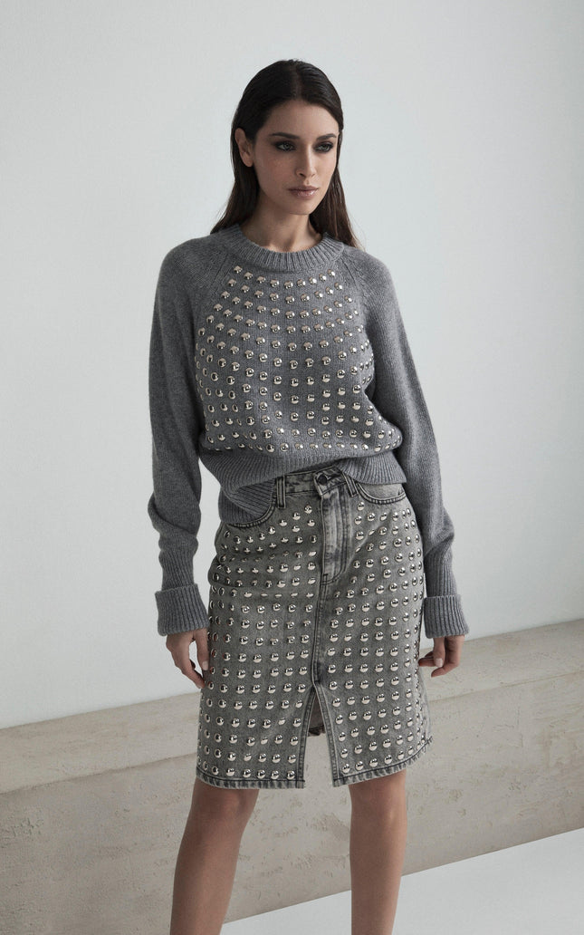 Woman wearing a grey studded sweater and matching studded denim skirt, front slit