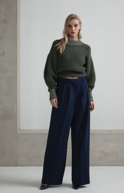 Woman in chunky green sweater with crystal cuffs and navy wide-leg trousers