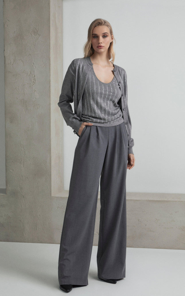 Woman in a grey pantsuit with wide-leg trousers and a sparkling striped top