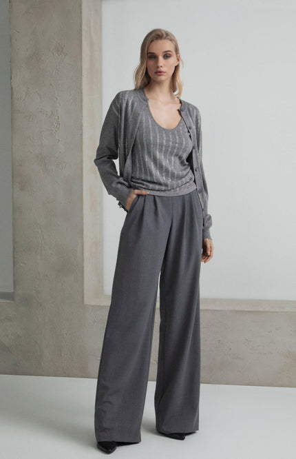 Woman in a grey pantsuit with wide-leg trousers and a sparkling striped top