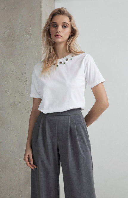 Woman in white embellished t-shirt and gray high-waisted pleated trousers