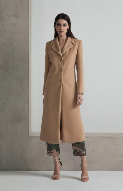 Woman in long camel coat with rhinestone collar, camouflage pants, and nude heels
