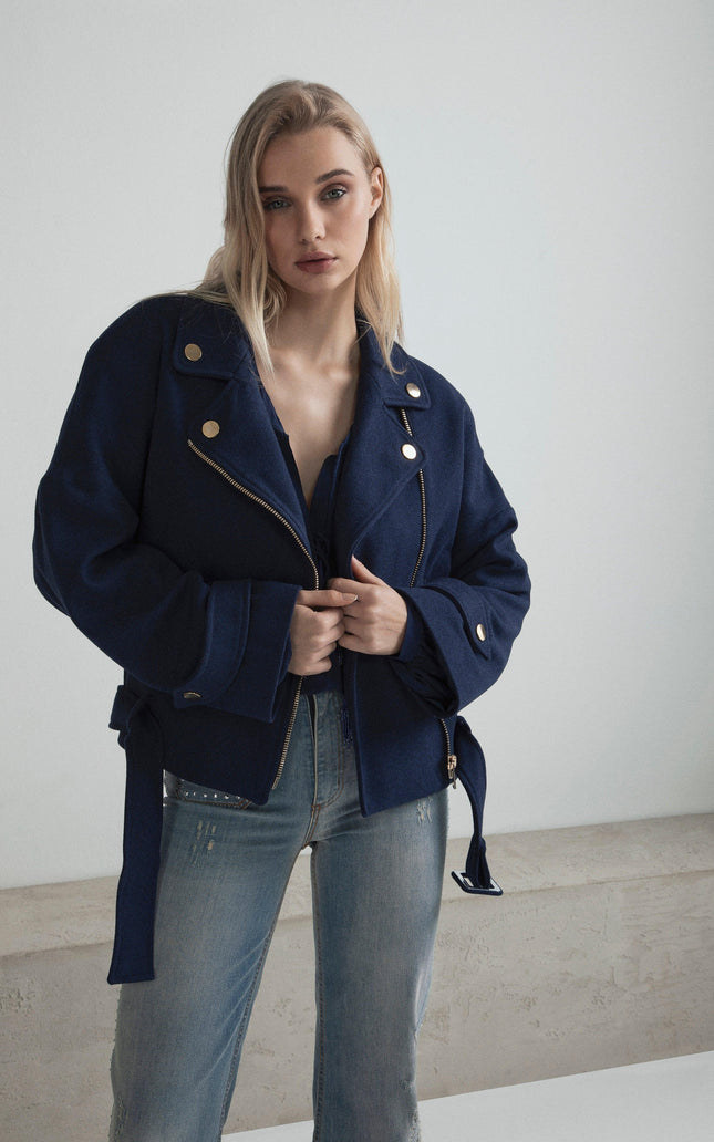 Woman wearing a navy blue belted jacket with gold buttons and light blue jeans