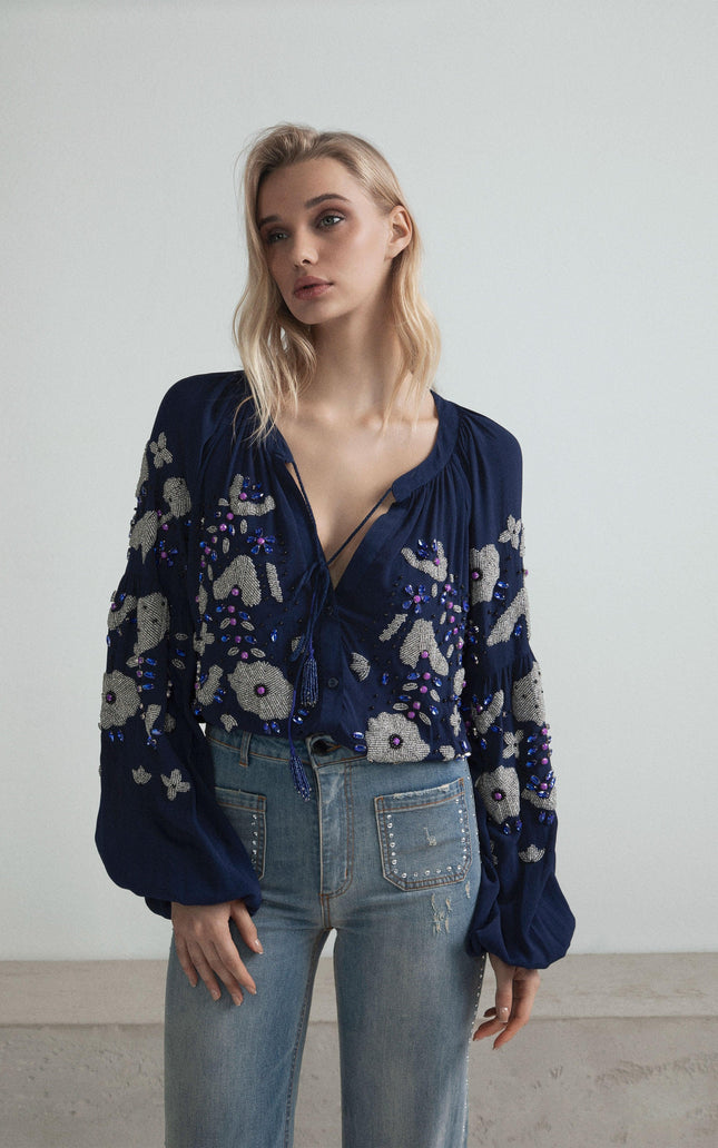 Woman wearing blue embroidered blouse with balloon sleeves and high-waisted jeans