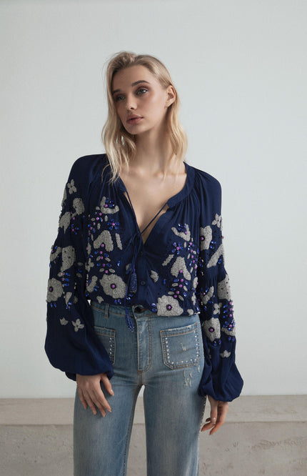 Woman wearing blue embroidered blouse with balloon sleeves and high-waisted jeans