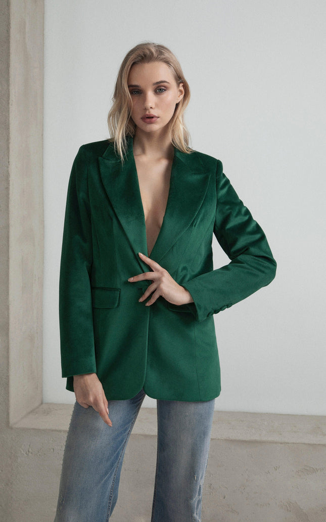 Woman in green velvet blazer and jeans, modern fashion indoor setting
