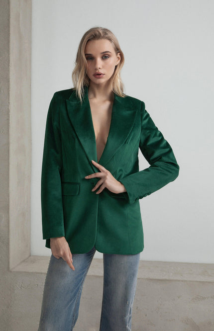 Woman in green velvet blazer and jeans, modern fashion indoor setting