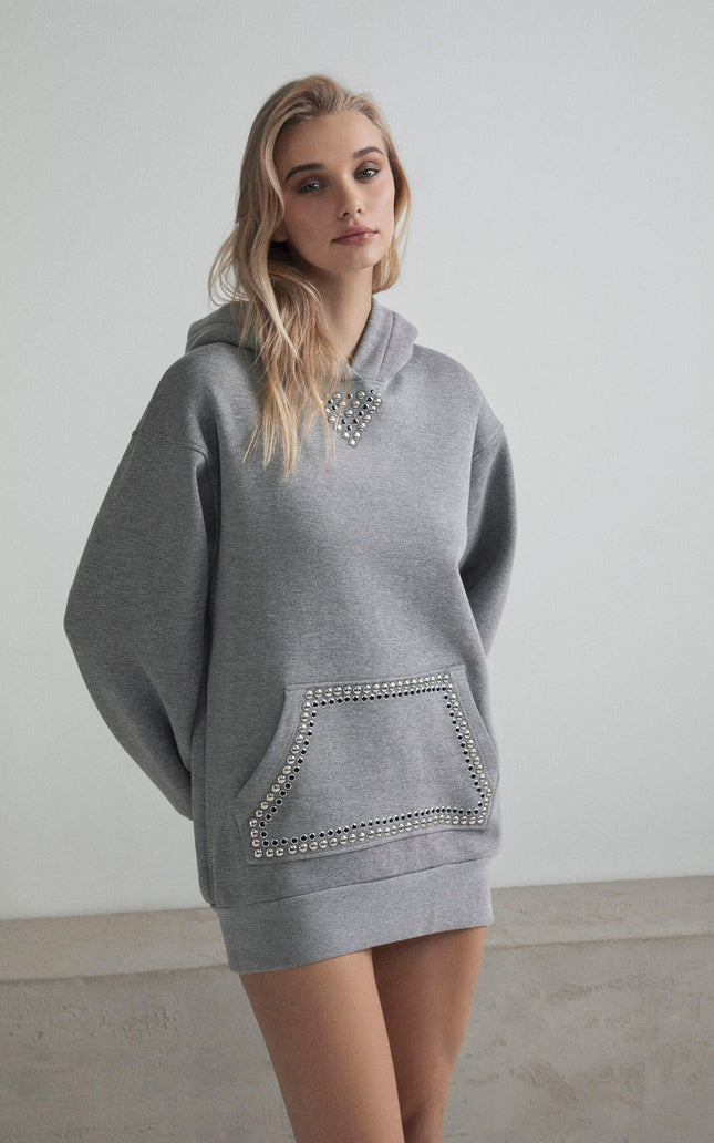 Woman wearing oversized grey hoodie with metallic studs on collar and pocket