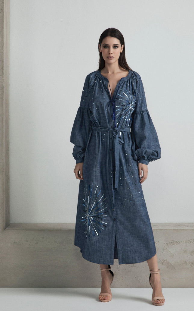 Woman wearing a denim belted midi dress with sequin starburst details and long sleeves