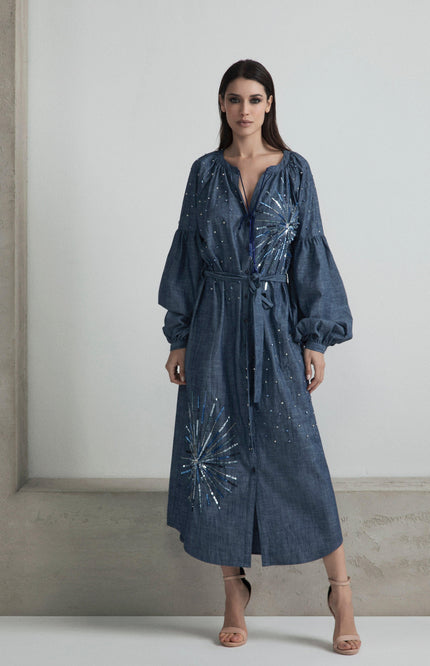 Woman wearing a denim belted midi dress with sequin starburst details and long sleeves