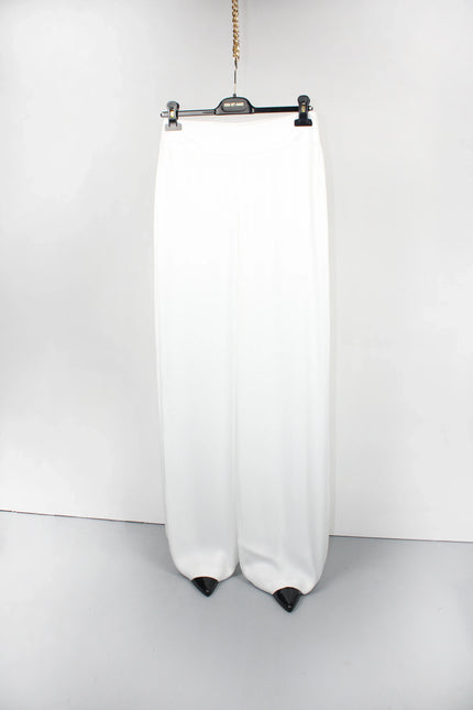 Wide-leg white pants with black pointed hems, hanging on a hanger against a white background