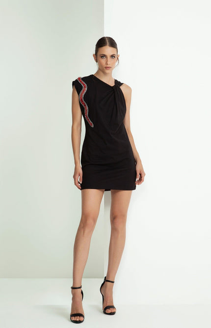Woman in a black mini dress with red and silver snake detail on shoulder, high heels