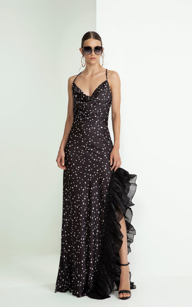 Woman wearing a black star print satin evening dress with ruffled slit and spaghetti straps.