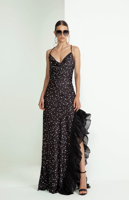 Woman wearing a black star print satin evening dress with ruffled slit and spaghetti straps.