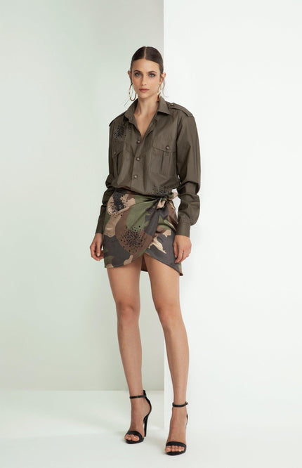 Woman in khaki shirt with black details and camo wrap mini skirt, high heels