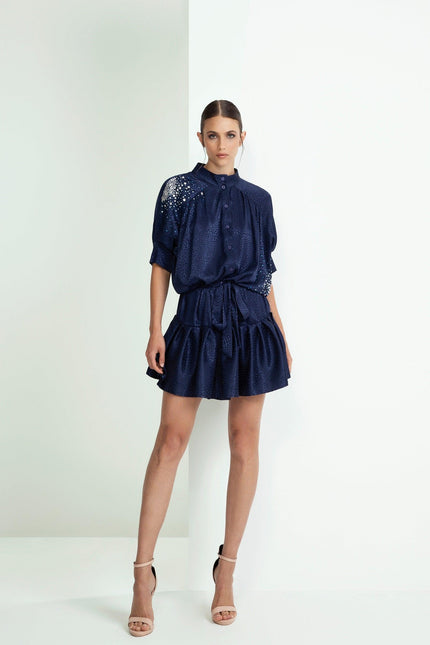 Woman wearing navy blue satin mini dress with short sleeves and embellished shoulder