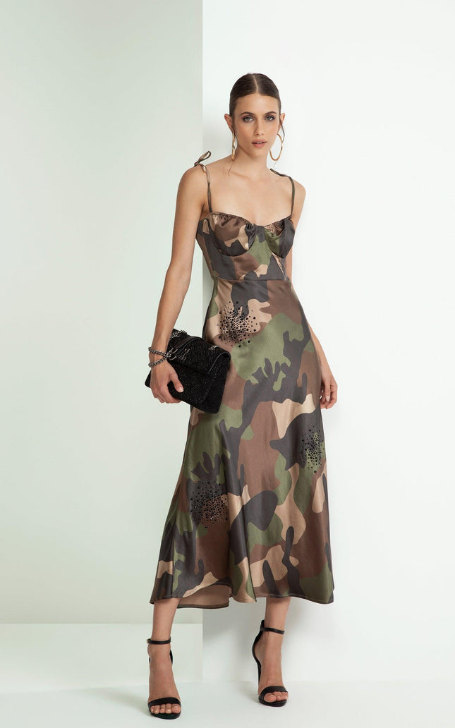 Woman wearing a camouflage print slip dress with shoulder ties, black clutch, and strappy heels