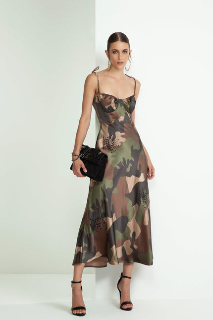 Woman wearing a camouflage print slip dress with shoulder ties, black clutch, and strappy heels