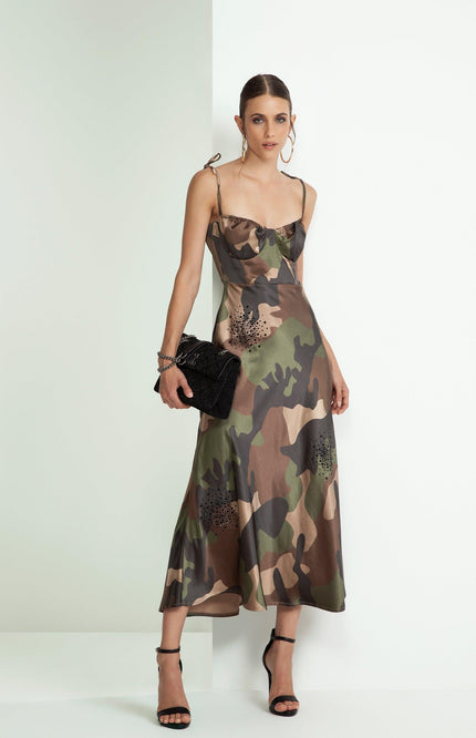 Woman wearing a camouflage print slip dress with shoulder ties, black clutch, and strappy heels