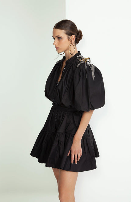 Woman in short black puff sleeve dress with embellished shoulder, side view, fashion look